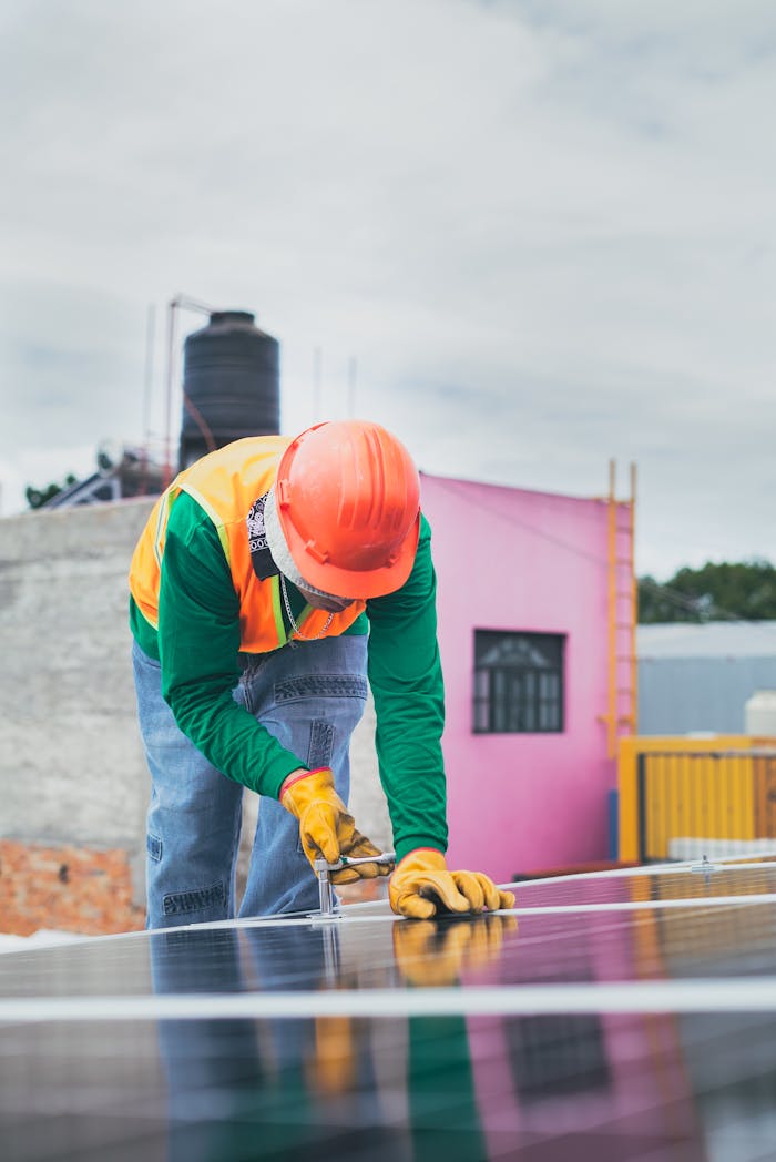 About A solar technician working outdoors installing photovoltaic panels with safety gear.